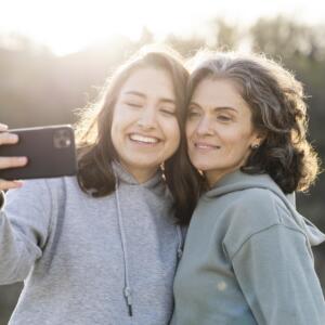 Smiley daughter taking selfie with her mother outdoors