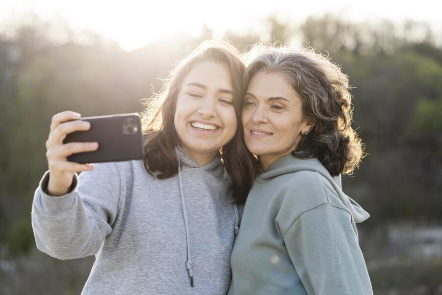 Smiley daughter taking selfie with her mother outdoors